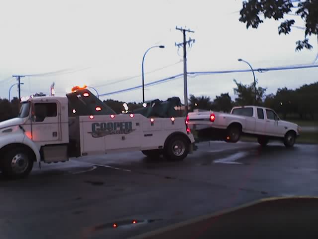 White pickup truck being towed by a tow truck, side view