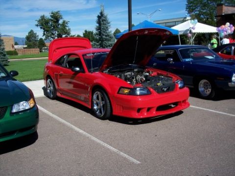 1972 Ford Ranchero - Red Ford Mustang from the early 2000s is displayed at a car show with other vehicles.