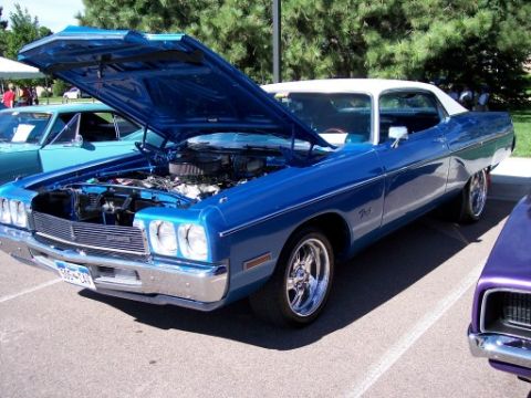 1972 Ford Ranchero - A blue 1972 Ford Gran Torino Sport coupe is displayed with its hood open, revealing the engine. A white vinyl roof tops the vehicle.
