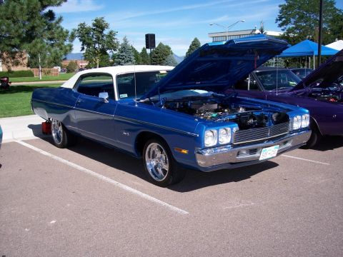 1972 Ford Ranchero - A blue coupe with its hood open is parked at an outdoor event, with another vehicle visible to its right.