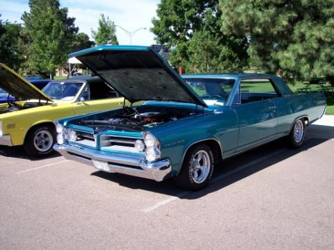 1972 Ford Ranchero - A teal 1965 Pontiac Grand Prix is displayed with its hood open at a car show.