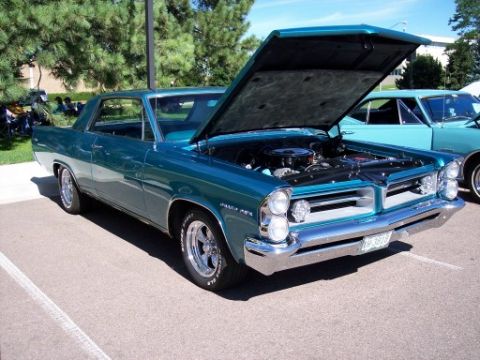 1972 Ford Ranchero - Teal 1964 Pontiac Grand Prix at a car show, hood up, with another car visible behind.
