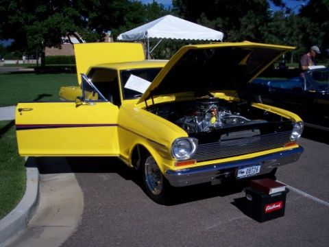 1972 Ford Ranchero - A bright yellow 1966 Chevrolet Nova coupe is displayed with its hood and driver's door open at a car show.