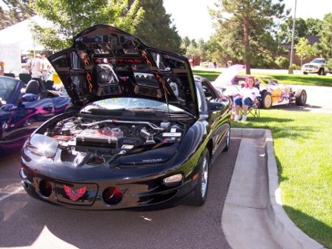 1972 Ford Ranchero - Black Pontiac Firebird displayed at a car show with its hood open.