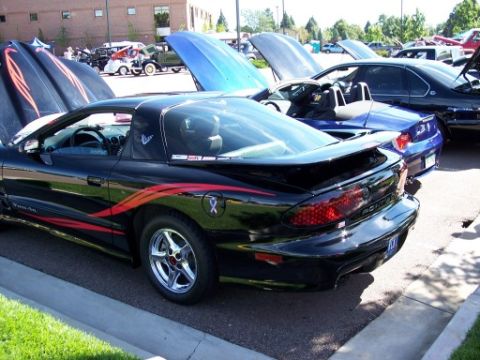 1972 Ford Ranchero - A black Pontiac Firebird Trans Am is parked with its hood open, alongside other vehicles at an outdoor car show.