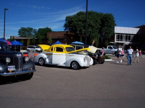 1972 Ford Ranchero - Several vehicles are parked in a lot on a sunny day, with people milling around.