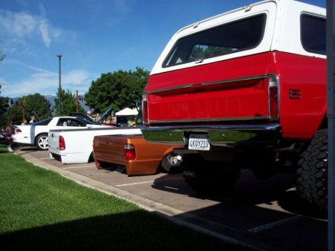 1972 Ford Ranchero - Multiple vehicles are parked in a lot under a blue sky with scattered clouds.