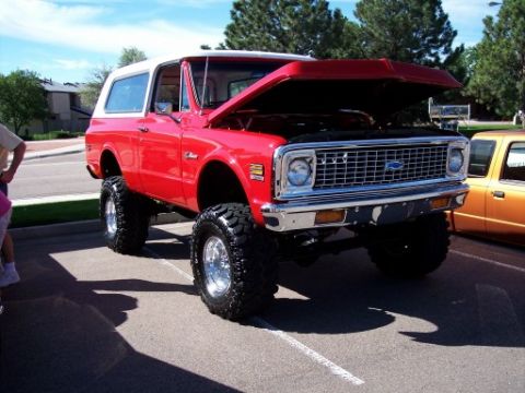 1972 Ford Ranchero - Lifted red 1971 Chevrolet K5 Blazer at a car show, hood up, with another vehicle beside it.