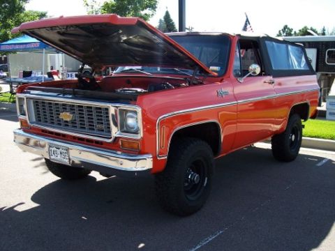 1972 Ford Ranchero - A red 1973 Chevrolet K5 Blazer is parked with its hood open, displaying its engine and chrome grille.