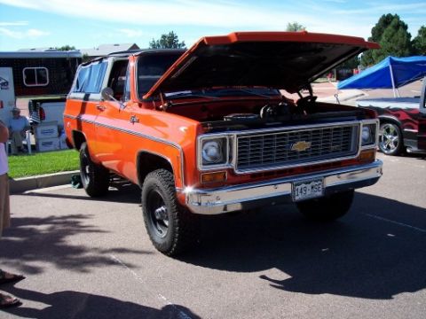 1972 Ford Ranchero - This orange SUV, likely a 1973 model, is displayed with its hood open at a car show.