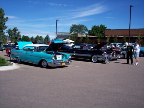 1972 Ford Ranchero - A turquoise and white 1957 Chevrolet Bel Air is displayed with its hood open at a car show, alongside other classic vehicles.