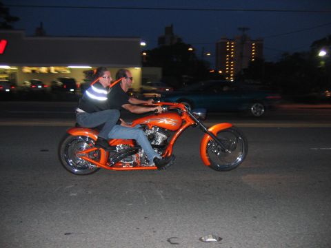 1992 Ford Mustang - A custom orange motorcycle carries two riders at night on a city street.