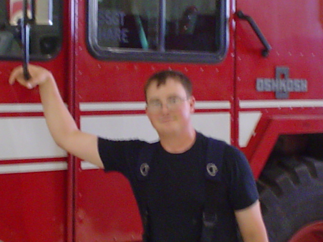 Red fire truck with white stripes and a man leaning on it