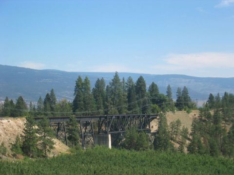 1990 Ford Bronco - A large railroad bridge spans a valley, surrounded by trees and distant hills under a clear blue sky.