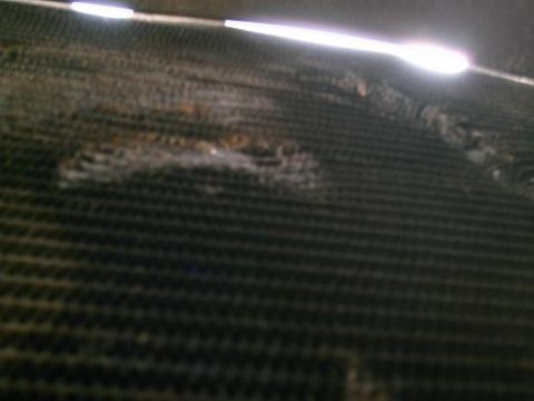 1986 Ford Bronco - The radiator fins are bent and damaged, showing signs of wear and tear.