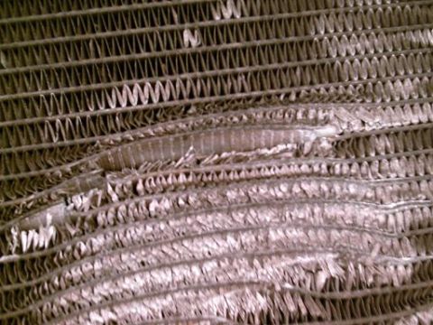 1986 Ford Bronco - Radiator fins are bent and torn, indicating damage to the cooling system component.