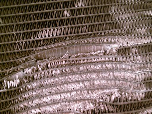 Close-up of damaged radiator fins with bent and torn metal