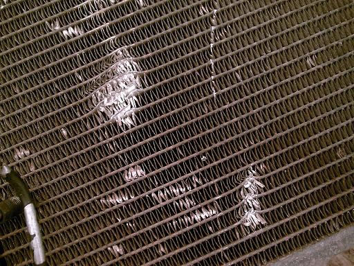 Close-up of bent and damaged radiator fins with some white residue