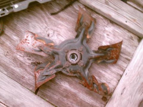 1986 Ford Bronco - A heavily rusted radiator fan blade is shown resting on a wooden surface.