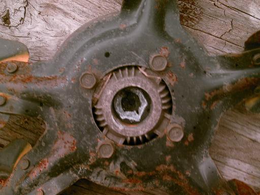 Rusted metal part with hexagonal bolt head and gear teeth