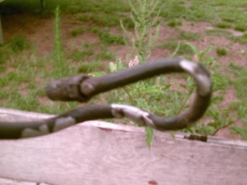 1986 Ford Bronco - A bent metal pipe with a rough end is visible, resting on a wooden surface outdoors.