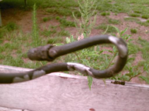 Bent metal pipe with a rough end, resting on a wooden surface