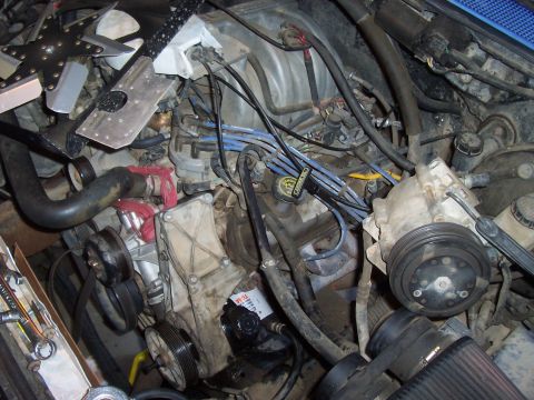 1994 Ford F-150 - The engine bay is filled with components, including spark plug wires, hoses, and pulleys, with some tools nearby.