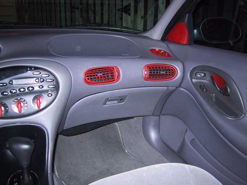 Passenger side of a gray dash with red-painted vents and door panel accents
