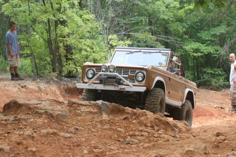 1990 Ford Bronco - A brown Ford Bronco navigates a rocky trail with two men observing.