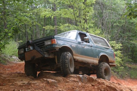 1990 Ford Bronco - This Ford Bronco is navigating a rocky, off-road trail in a wooded area.