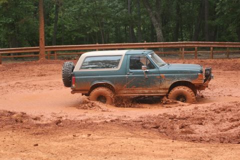 1990 Ford Bronco - This Ford Bronco is deep in the mud, with only its top and tires visible above the muck.
