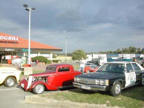1991 Ford Crown Victoria - Police car and hot rod parked outside a restaurant.