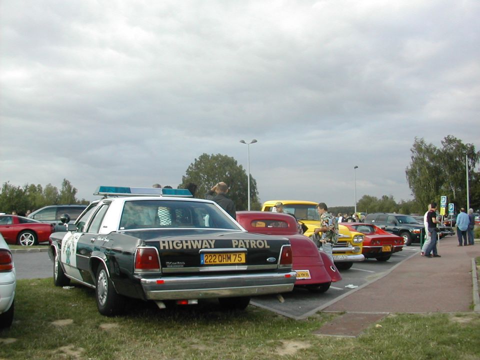 Police car with 'HIGHWAY PATROL' on back, parked in lot with other cars