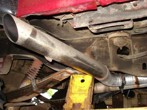 1994 Ford Bronco - The undercarriage of a red vehicle, with a focus on the exhaust system and suspension components.