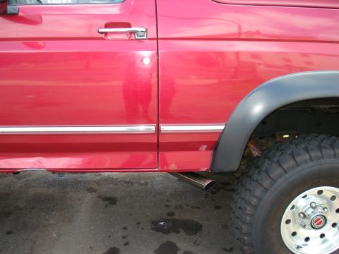 1994 Ford Bronco - Exhaust pipe visible on the side of a red 1994 Ford Bronco.