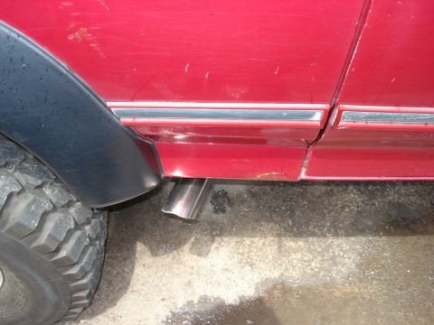 1994 Ford Bronco - A close-up view of a vehicle's exhaust pipe and fender flare.