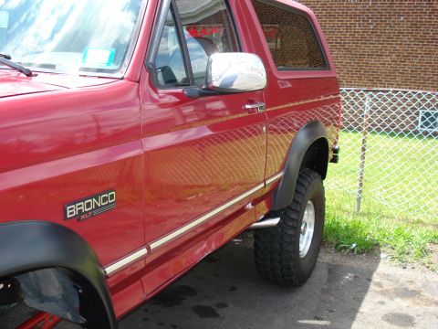 1994 Ford Bronco - Side profile of a red 1994 Ford Bronco XLT with chrome trim and fender flares.