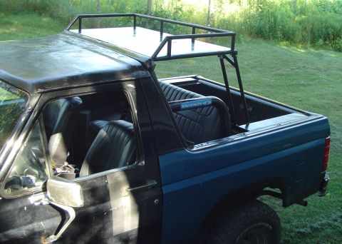 1986 Ford Bronco - This Ford Bronco features a custom roof rack and roll bar, with a dark blue exterior.