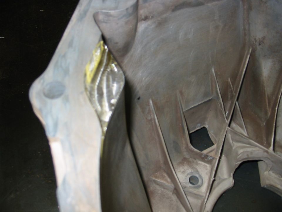 Close-up of a gray plastic automotive part with yellow tape visible in a crevice