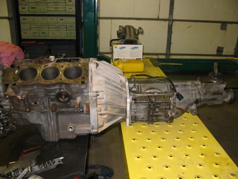 1993 Ford Taurus - Engine and transmission assembly displayed on a yellow platform in a workshop setting.