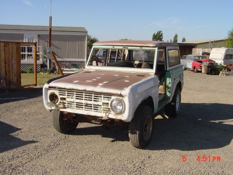 1991 Ford Explorer - A weathered Ford Bronco sits in a yard with other vehicles and trailers visible in the background.