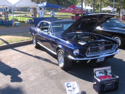 1989 Ford Mustang - A blue 1967 Ford Mustang is displayed with its hood open, parked next to another vehicle at an outdoor event.