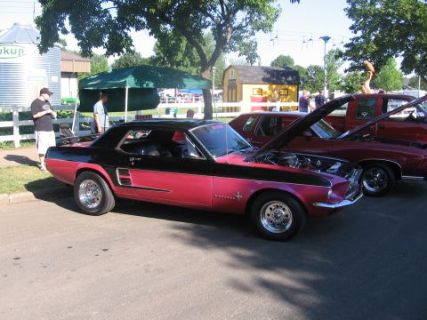 1989 Ford Mustang - A classic Mustang is displayed at an outdoor event with other vehicles.