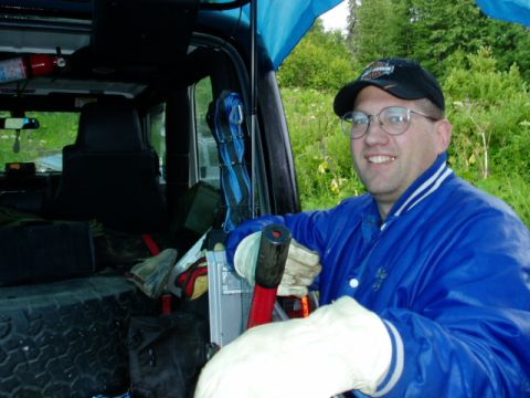 2000 Ford E350 - A man smiles from inside a vehicle, which is packed with various equipment and gear.