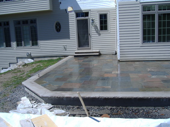 Construction scene with a newly laid stone patio and house exterior