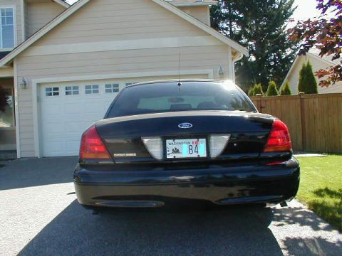 2002 Ford Crown Victoria - Rear view of a black 2002 Ford Crown Victoria parked in front of a garage.