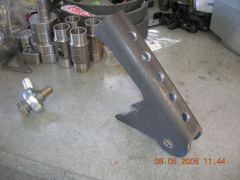 1996 Ford Bronco - A metal bracket and ball joint are shown on a workbench, with various metal parts in the background.