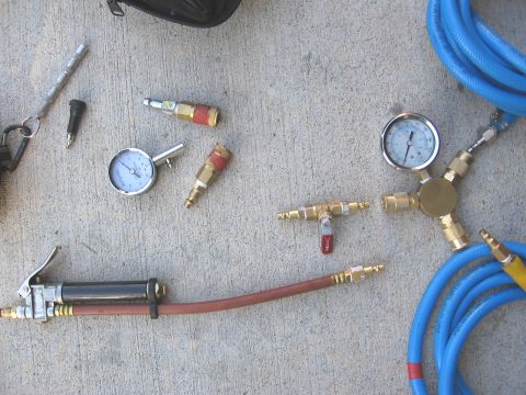 1994 Ford Bronco - Various air compressor accessories, including gauges, hoses, and quick-connect fittings, are arranged on a concrete surface.