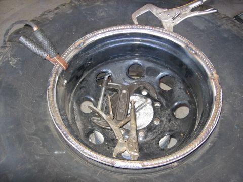 1994 Ford Bronco - Welding clamps are attached to a tire rim, which has a bead of weld material around its edge.