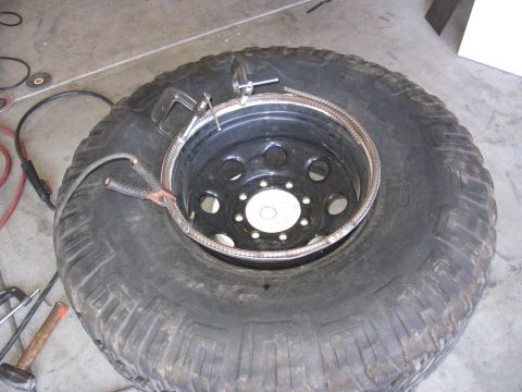 1994 Ford Bronco - Welding equipment attached to a tire and rim assembly, preparing for modification.